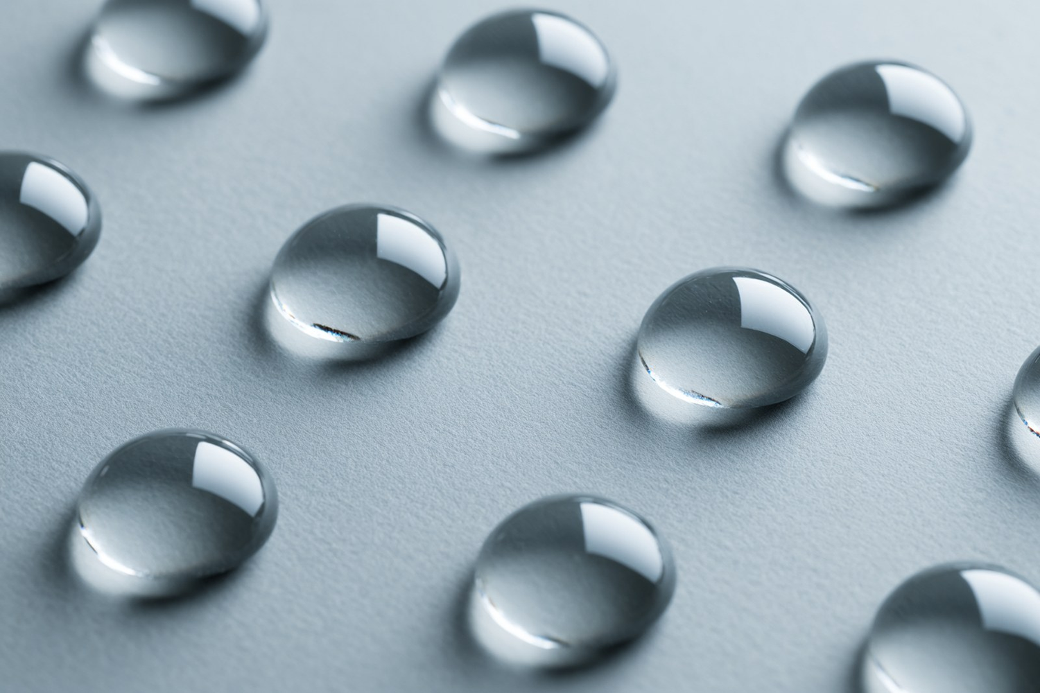 Evenly spaced clear droplets on a soft grey surface, a calm macro texture