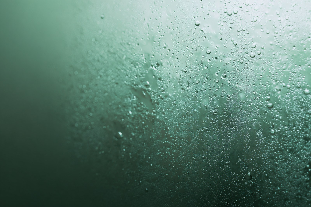 Fresh water droplets suspended in soft light, suggesting sun protection and freshness