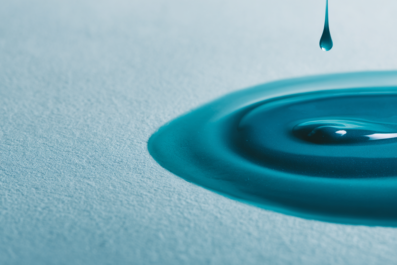 A calm teal ripple spreading on soft textured paper, editorial abstract