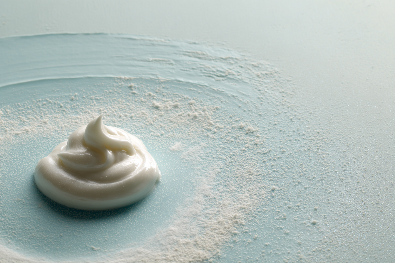A soft white cream swirl on a pale blue surface, editorial abstract