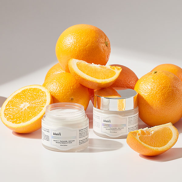 Freshly Juiced Vitamin E Mask product jars with oranges on a warm white background