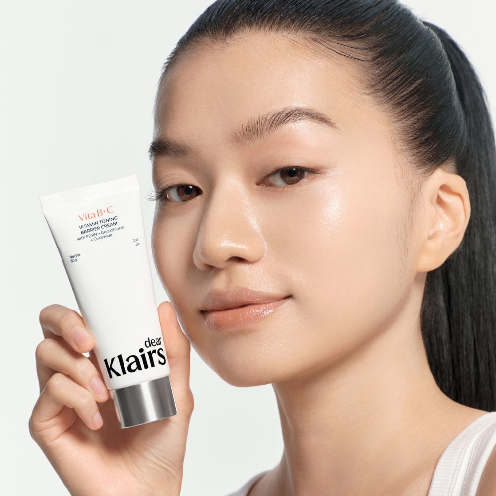 Model holding Vitamin Toning Barrier Cream with bright even-looking skin