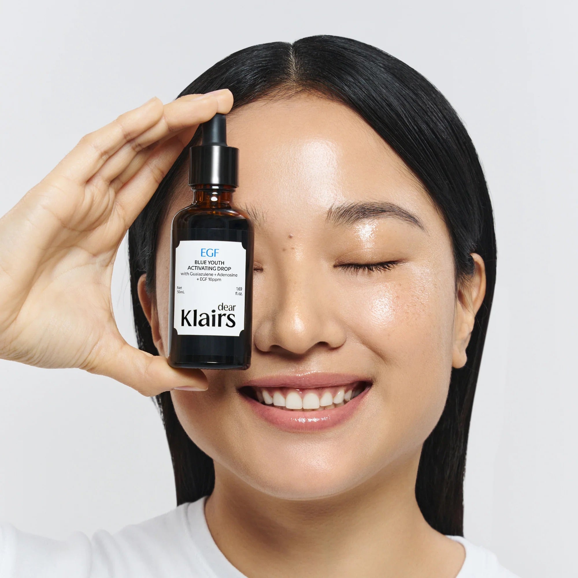 Dear, Klairs EGF Blue Youth Activating Drop held beside glowing skin